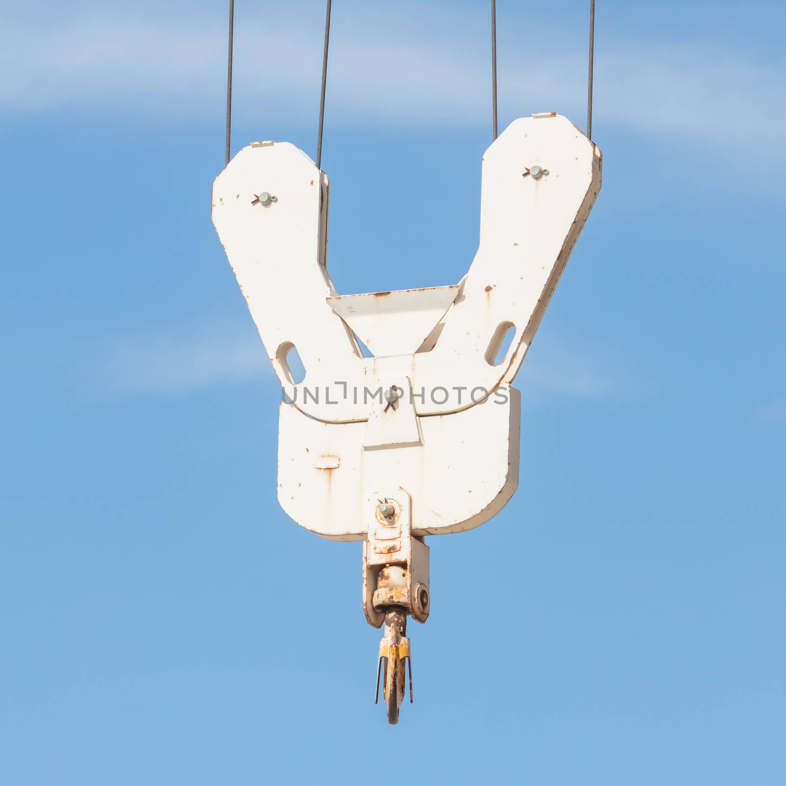 Old metal crane hook on blue sky background