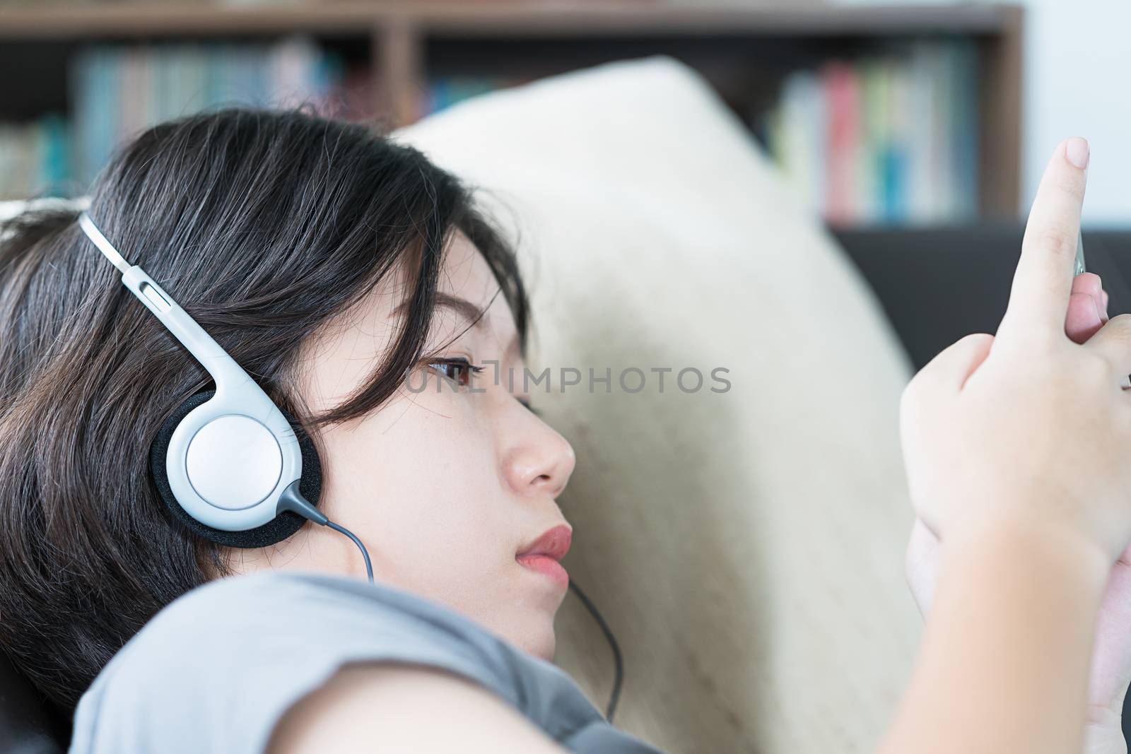 Close up young asian woman short hair listening music from mobile phone on the couch at home