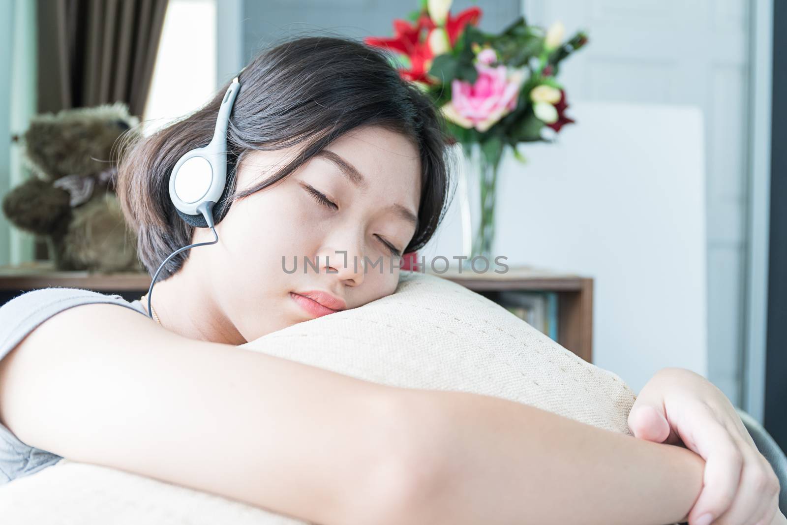 Close up young asian woman short hair listening music on the couch at home