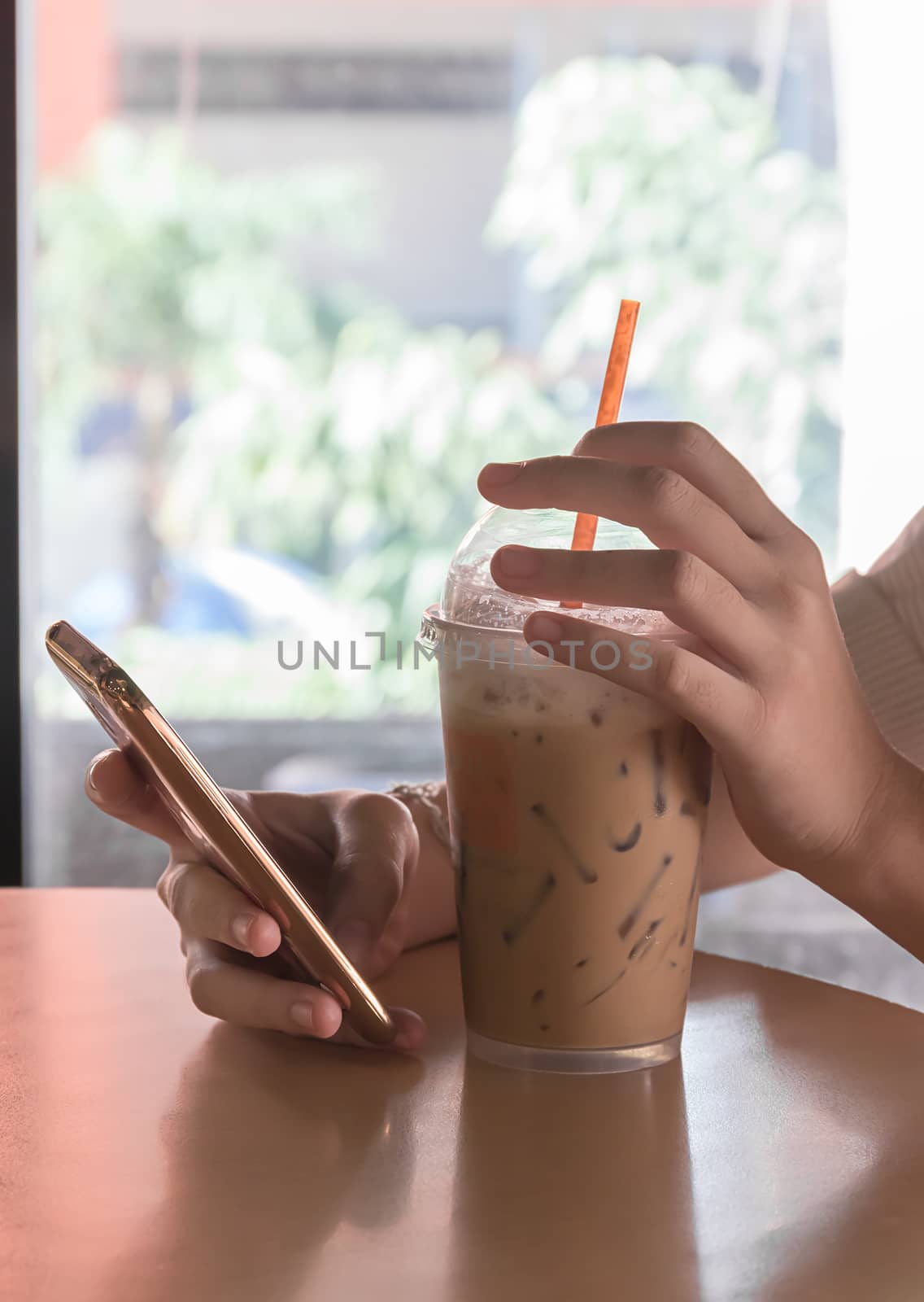 Hand woman using smartphone in coffee shop and a cup of coffee on the table with soft light vintage filter