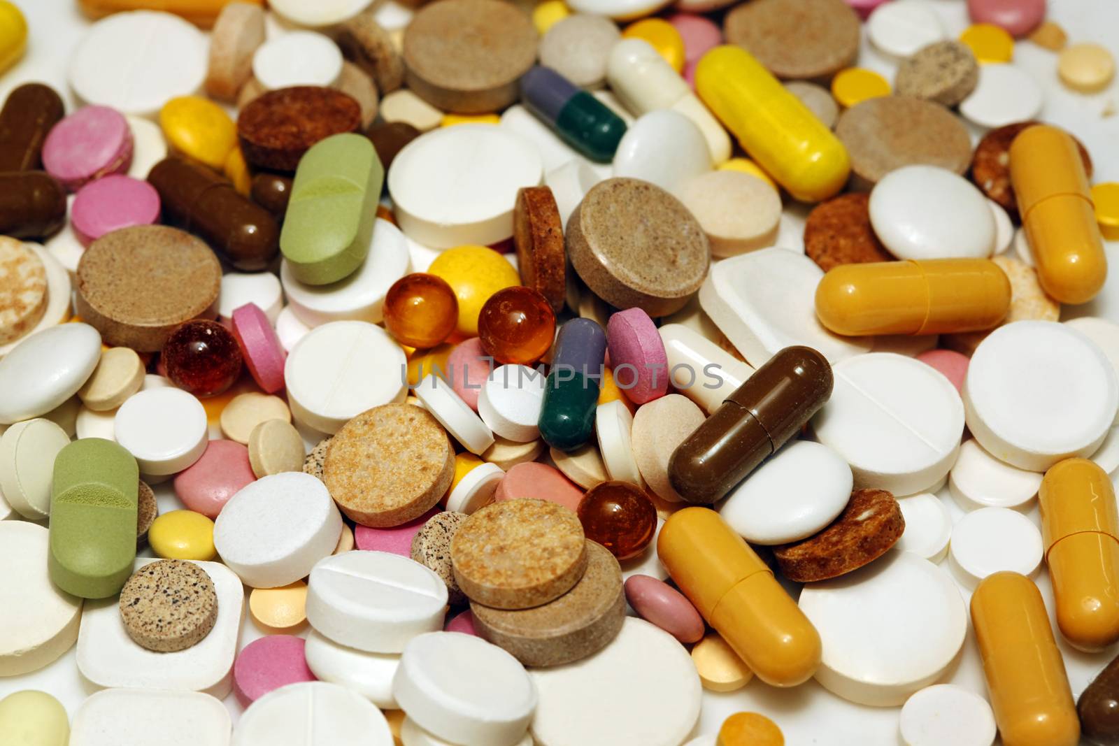 Assorted colorful pills and capsules on white background close up, horizontal, selective focus, medical concept