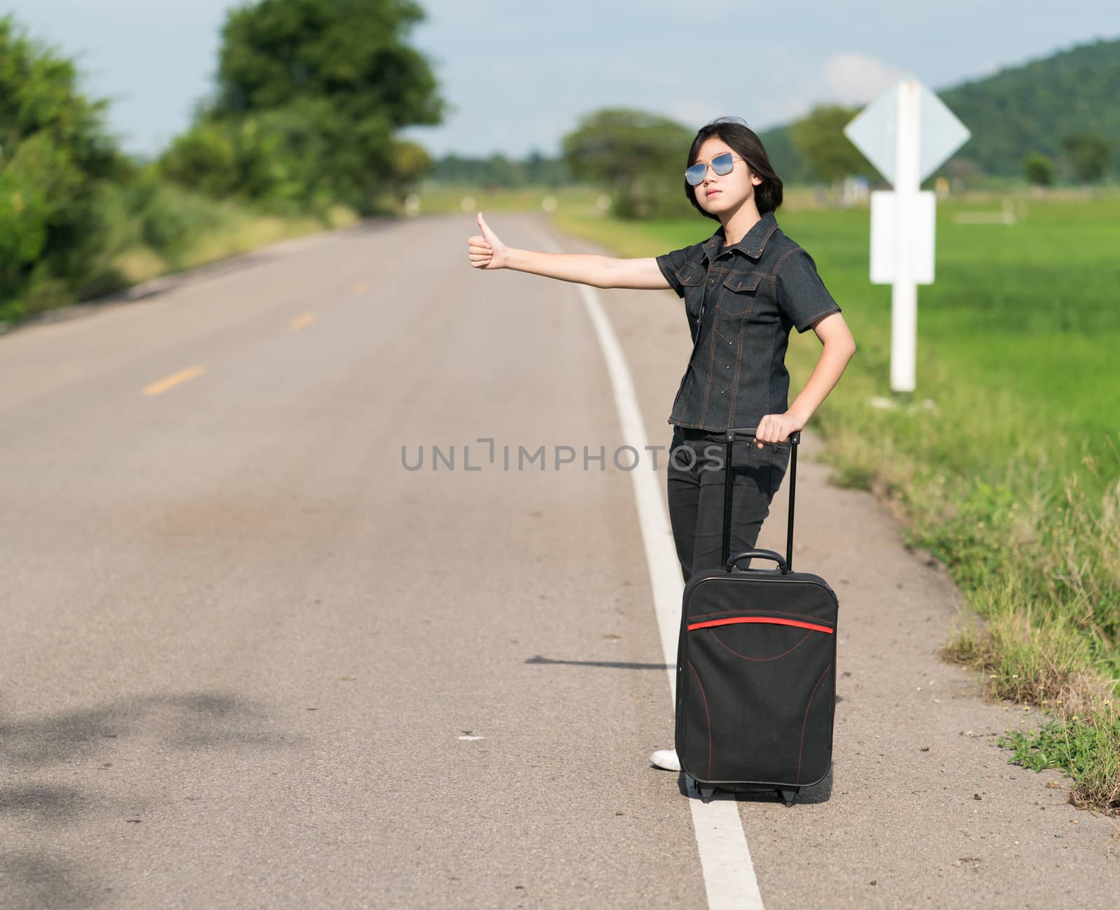 Woman short hair with luggage hitchhiking and thumbs up by stoonn