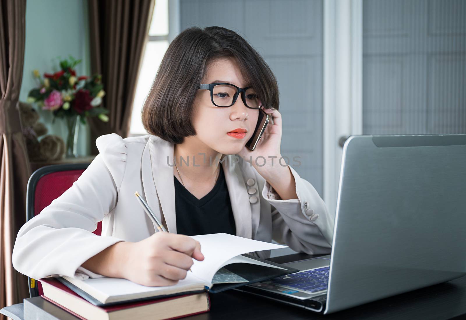 Woman working on laptop in home office by stoonn