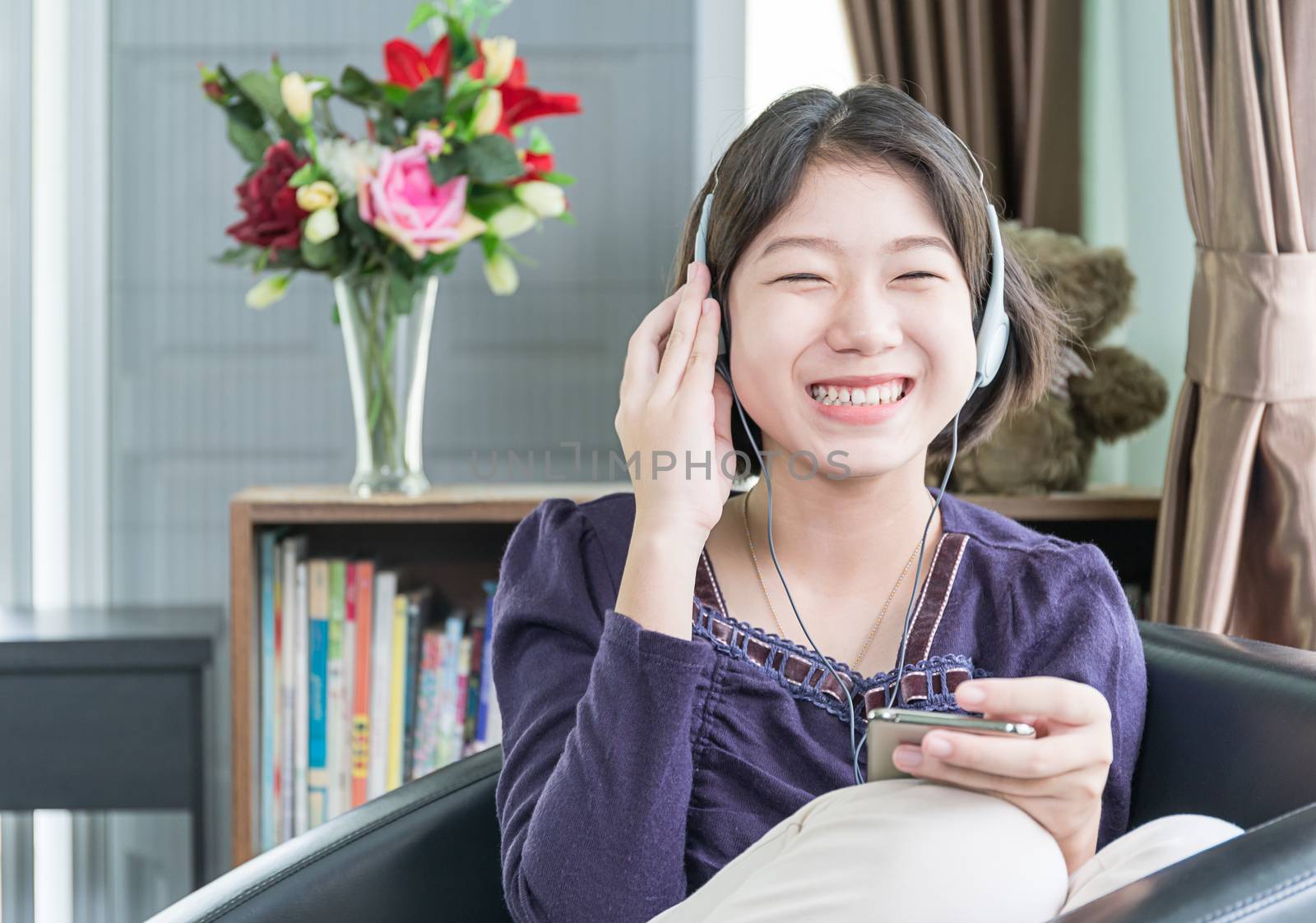 Young asian woman short hair listening music in living room by stoonn