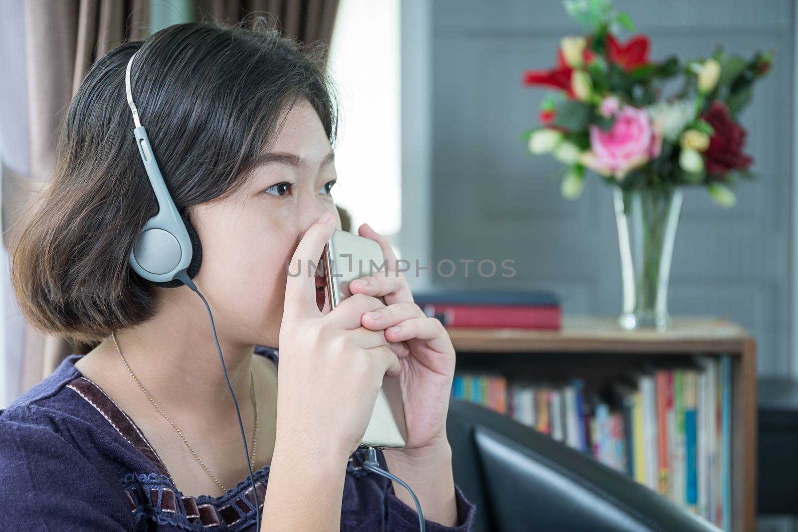 Close up beautiful young asian woman short hair listening music in living room at home