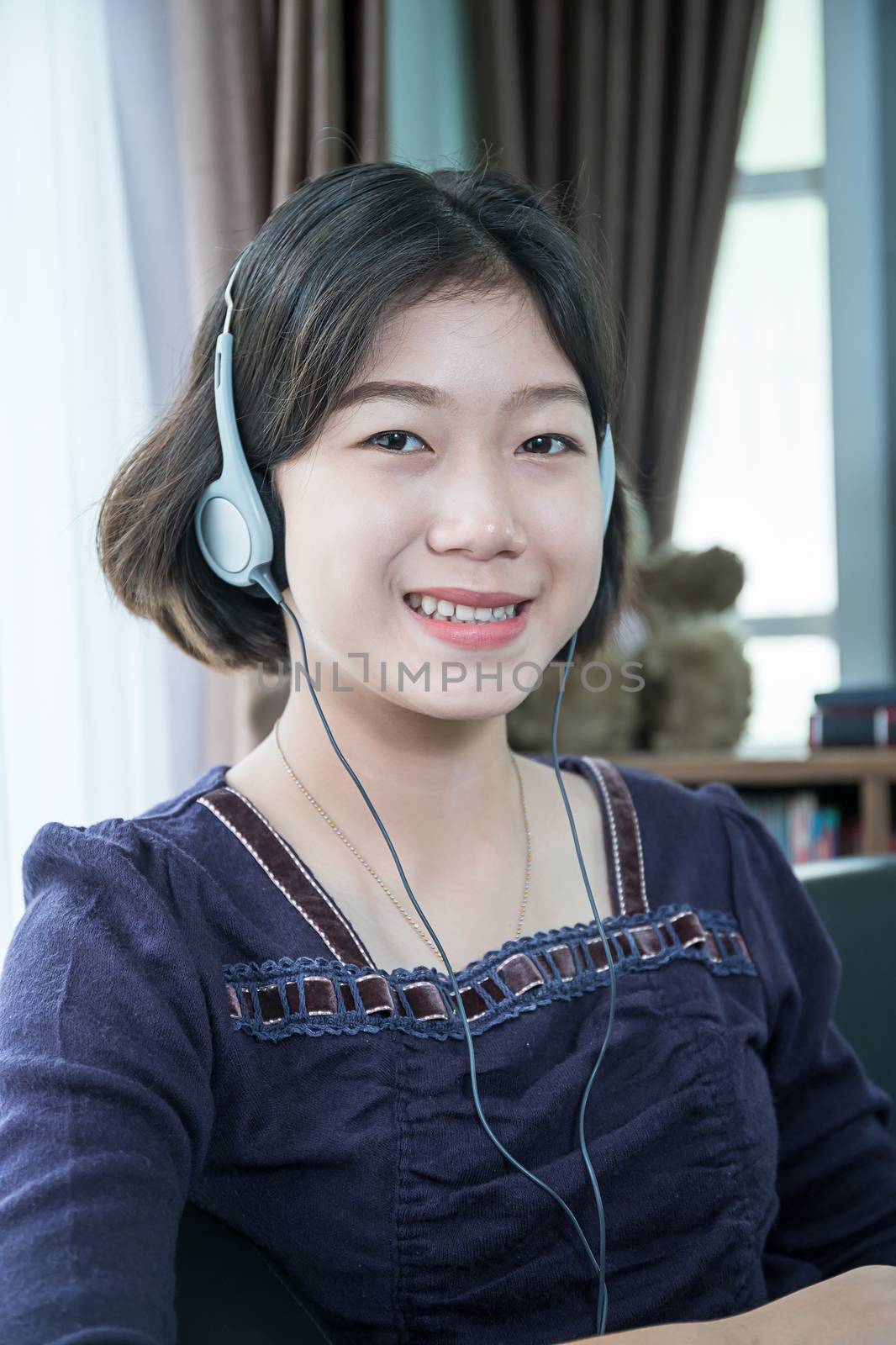 Close up beautiful young asian woman short hair listening music in living room at home