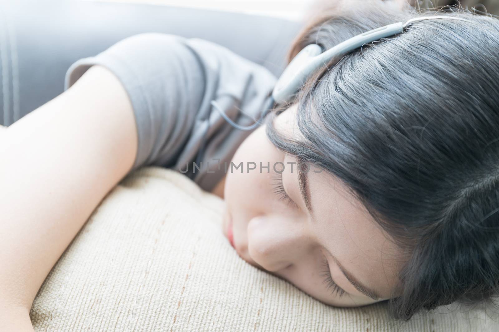 Close up beautiful young asian woman short hair listening music on the couch at home