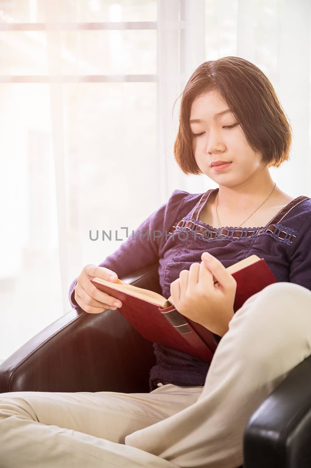 Young asian woman short hair read a book in living room by stoonn