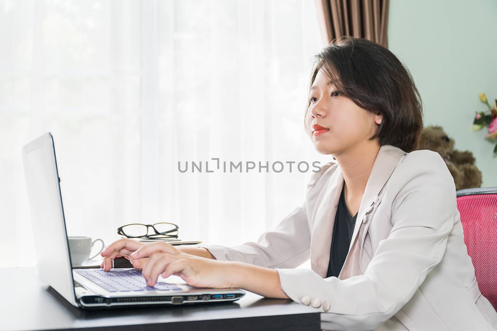 Young woman in smart casual wear working on laptop by stoonn