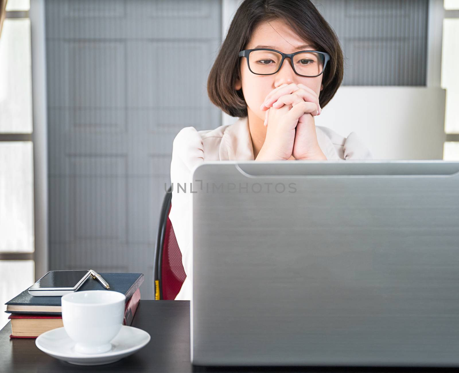 Young asian woman short hair in smart casual wear working on laptop while sitting near window in home office