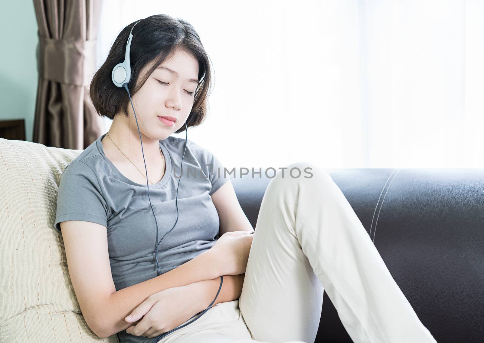 Close up young asian woman short hair listening music from mobile phone on the couch