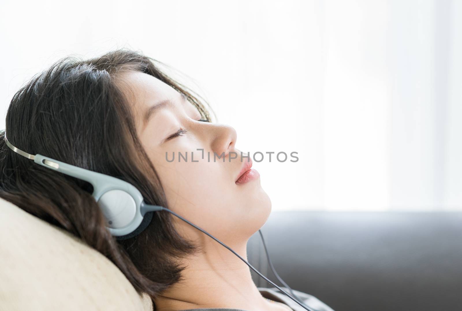 Close up young asian woman short hair listening music from mobile phone on the couch