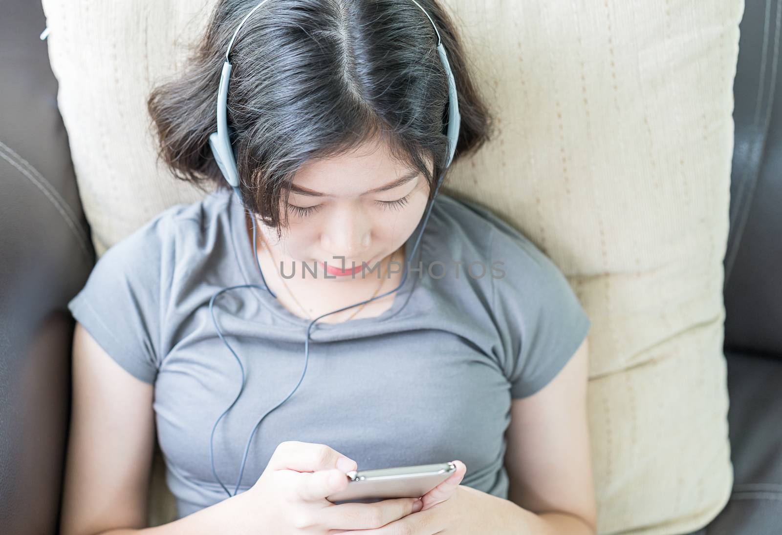 Close up young asian woman short hair listening music from mobile phone on the couch