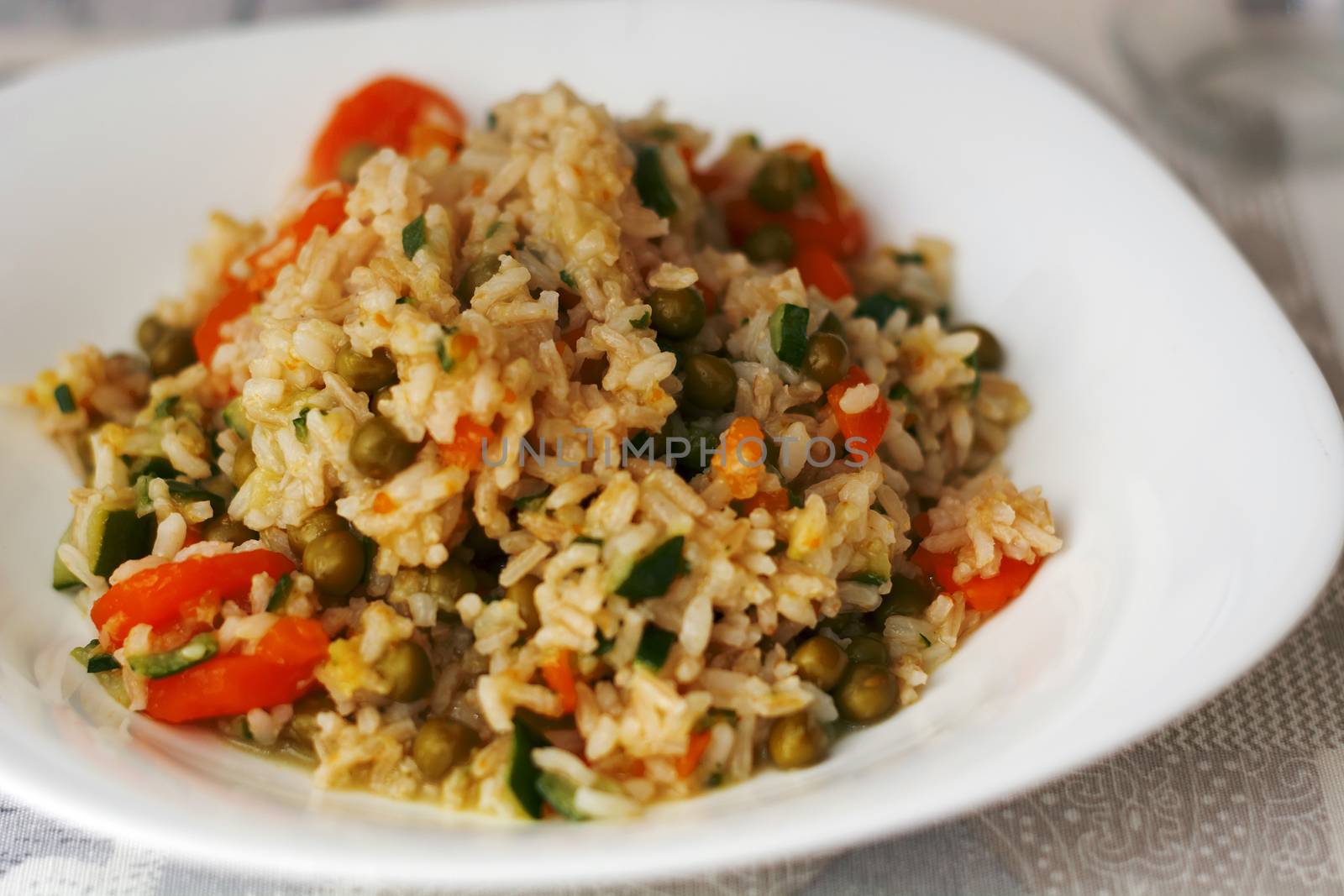Close up of a dish with rice, carrots, zucchini and peas