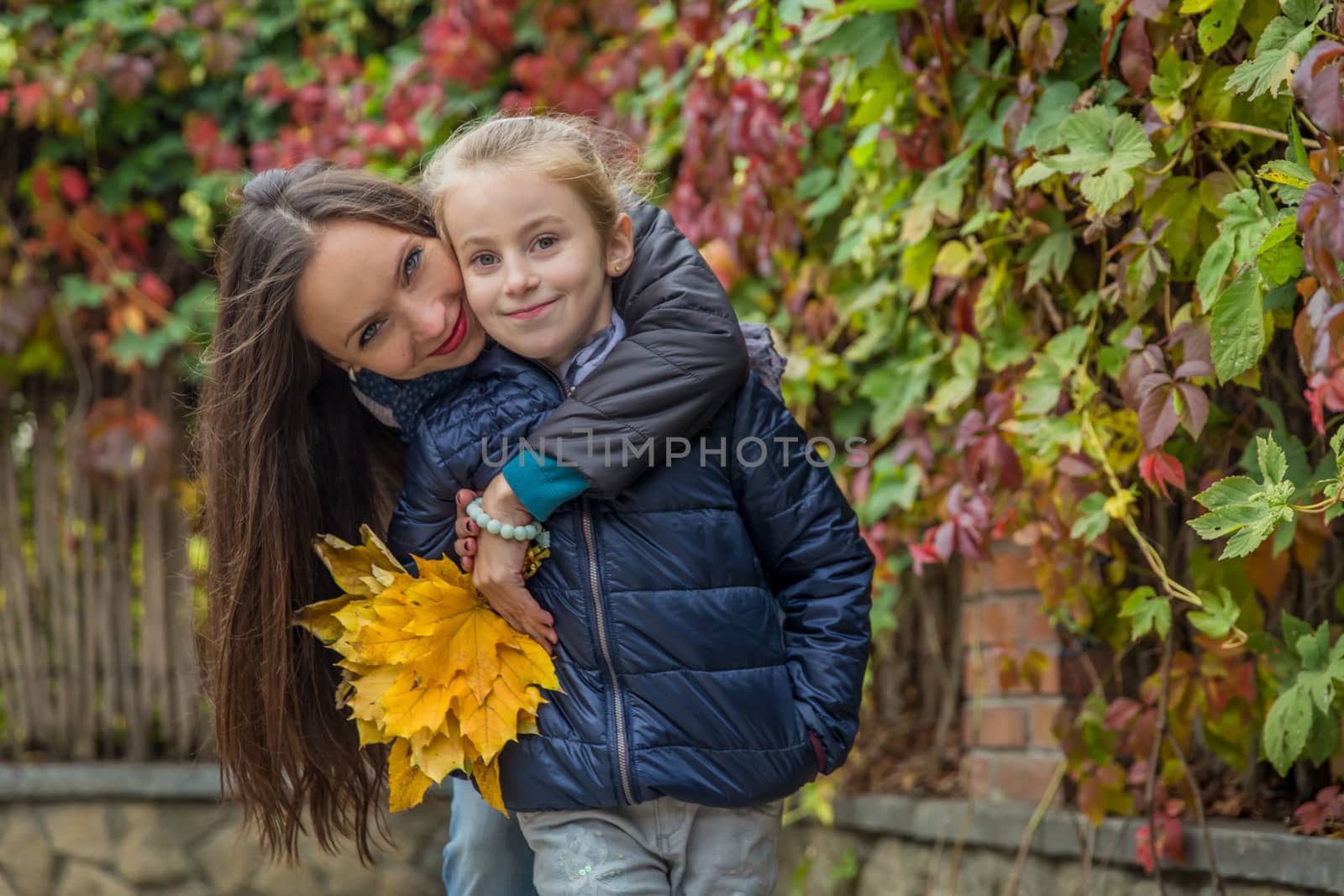 Mother hugging daughter among autumn