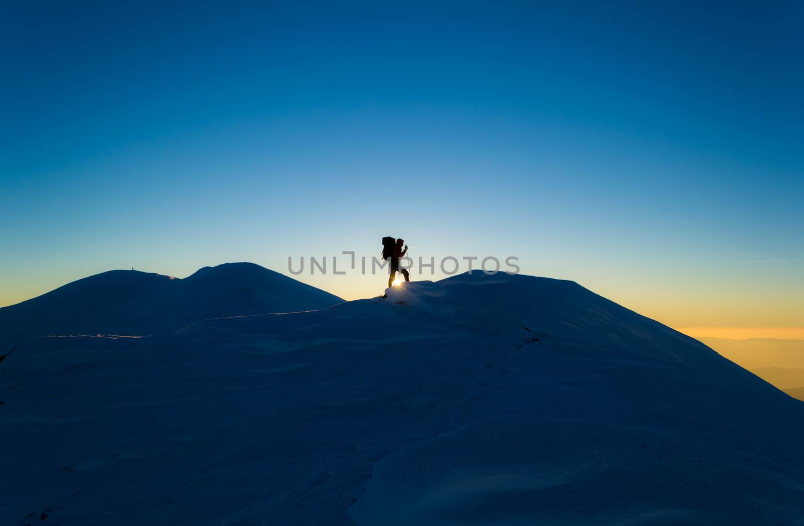 Men silhouette on a background of snowy mountains. Blue sky. Sunset in the Carpathians, Ukraine.