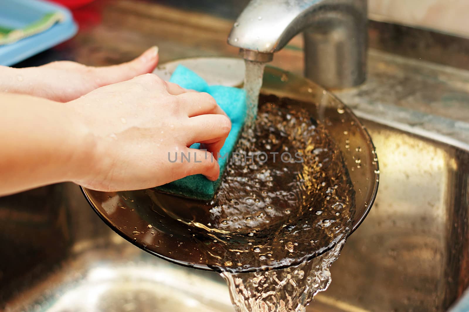 The woman washes plate by soft lip for utensils on the kitchen.