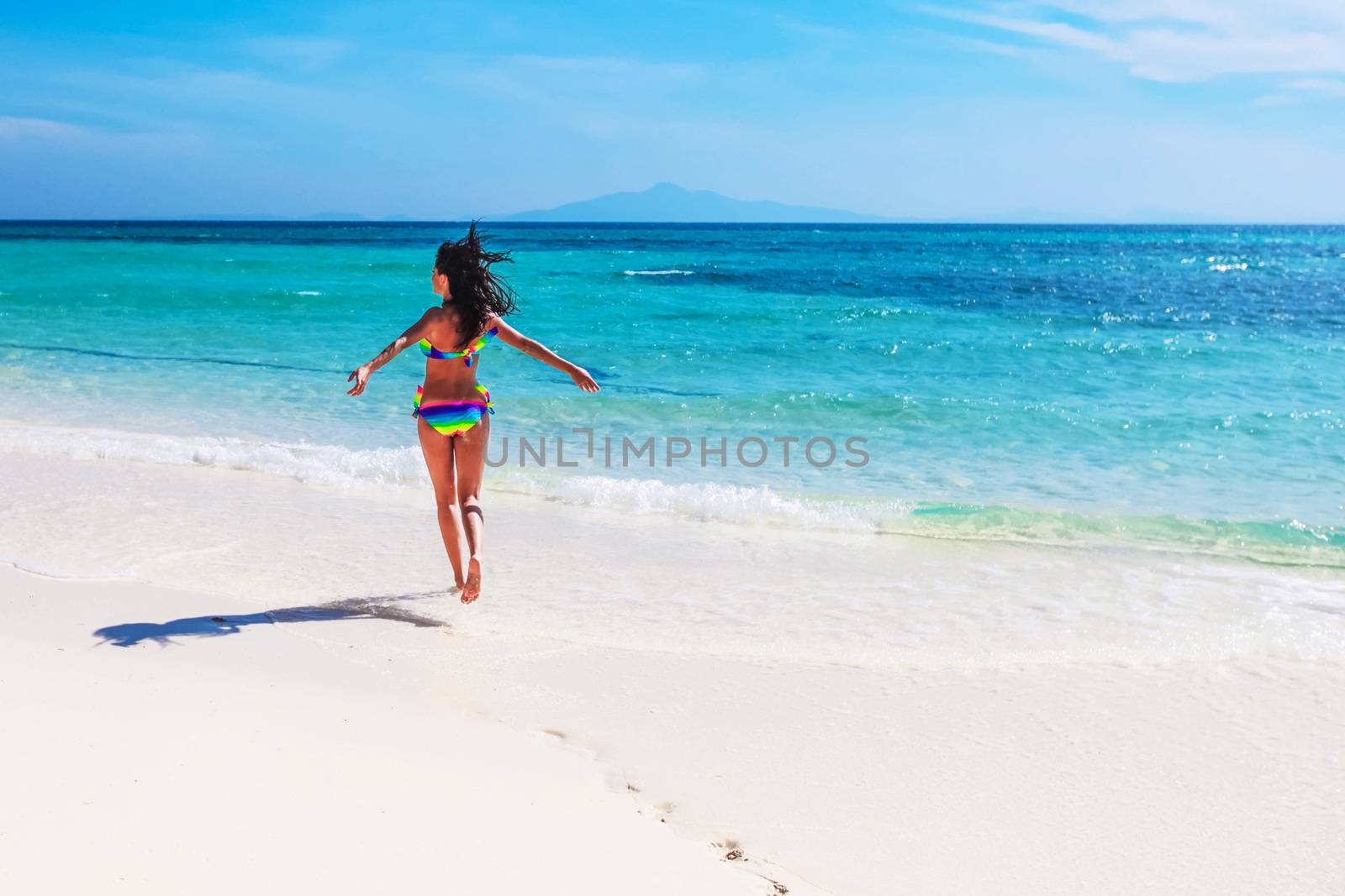 Beautiful happy girl running in tropical sea waves