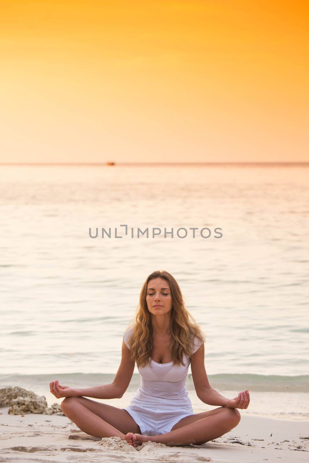 Woman practicing yoga on beach by Yellowj