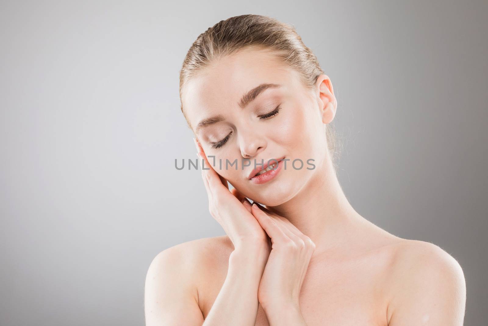 Beautiful young woman with clean fresh skin portrait on gray background with copy space
