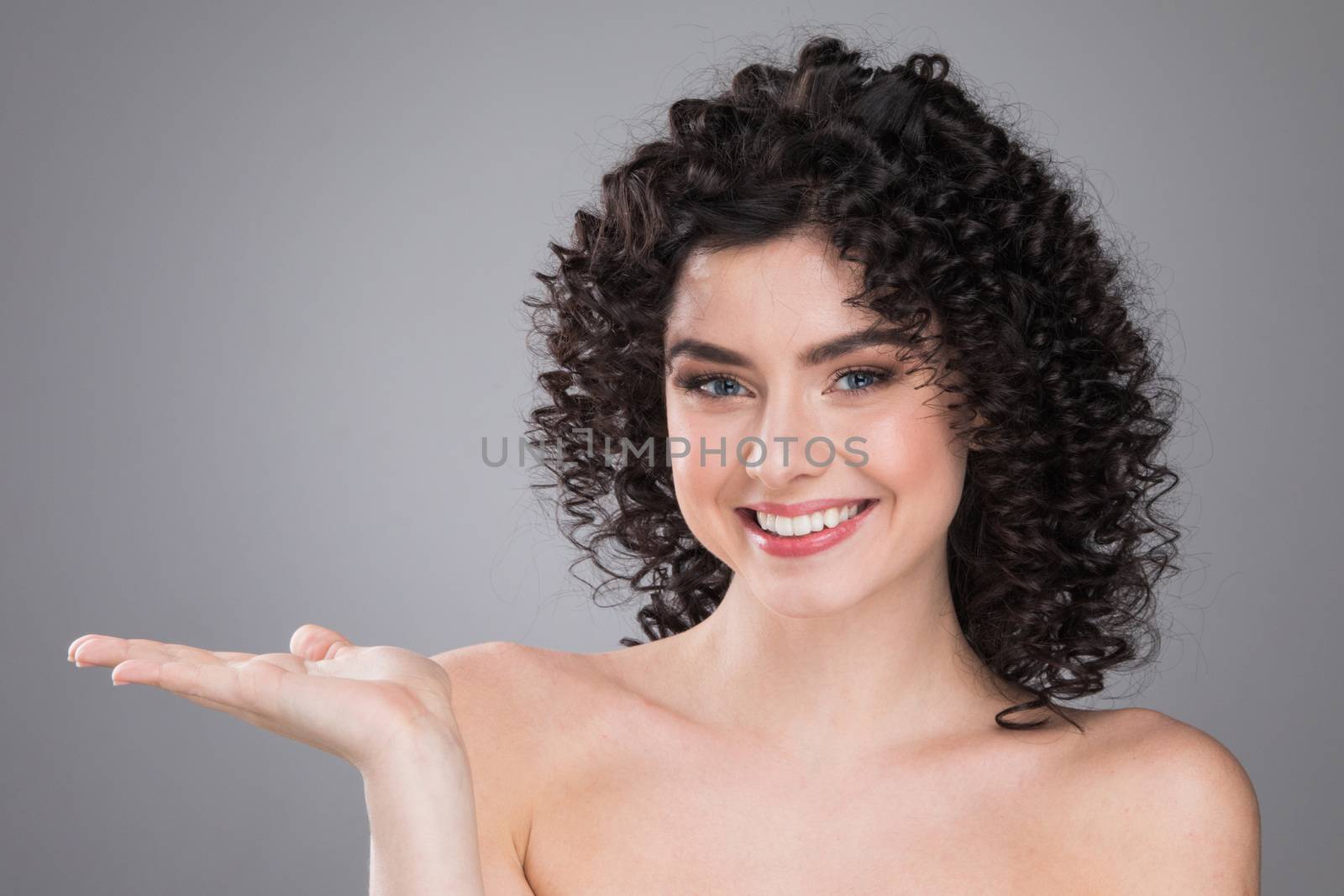 Portrait of beautiful smiling woman with curly hair, gray background