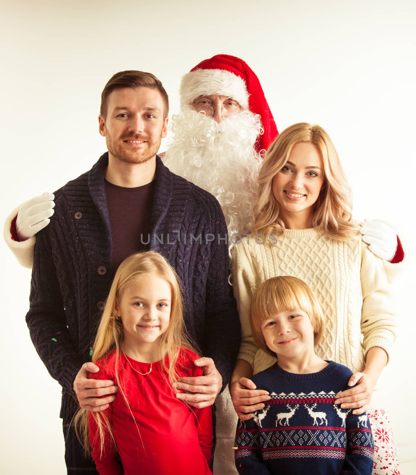 Christmas portrait of happy smiling family with two children ans Santa Claus embracing them