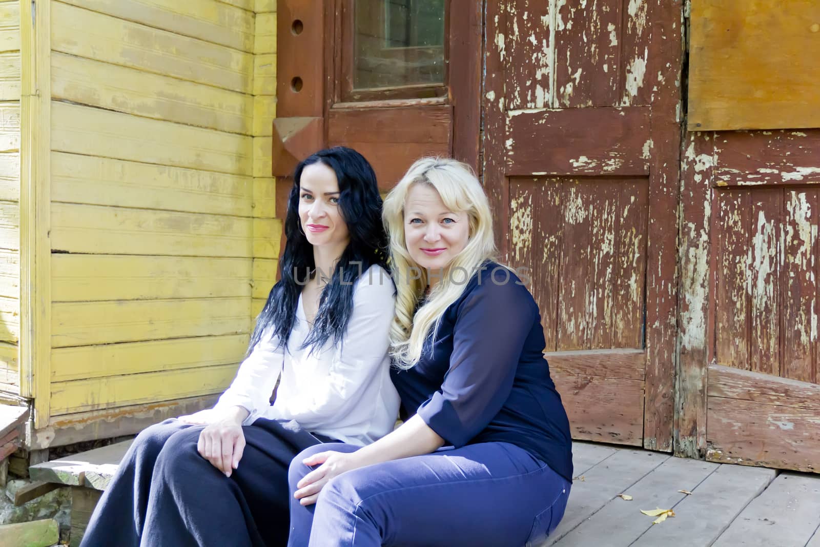 Two women are sitting on wooden porch
