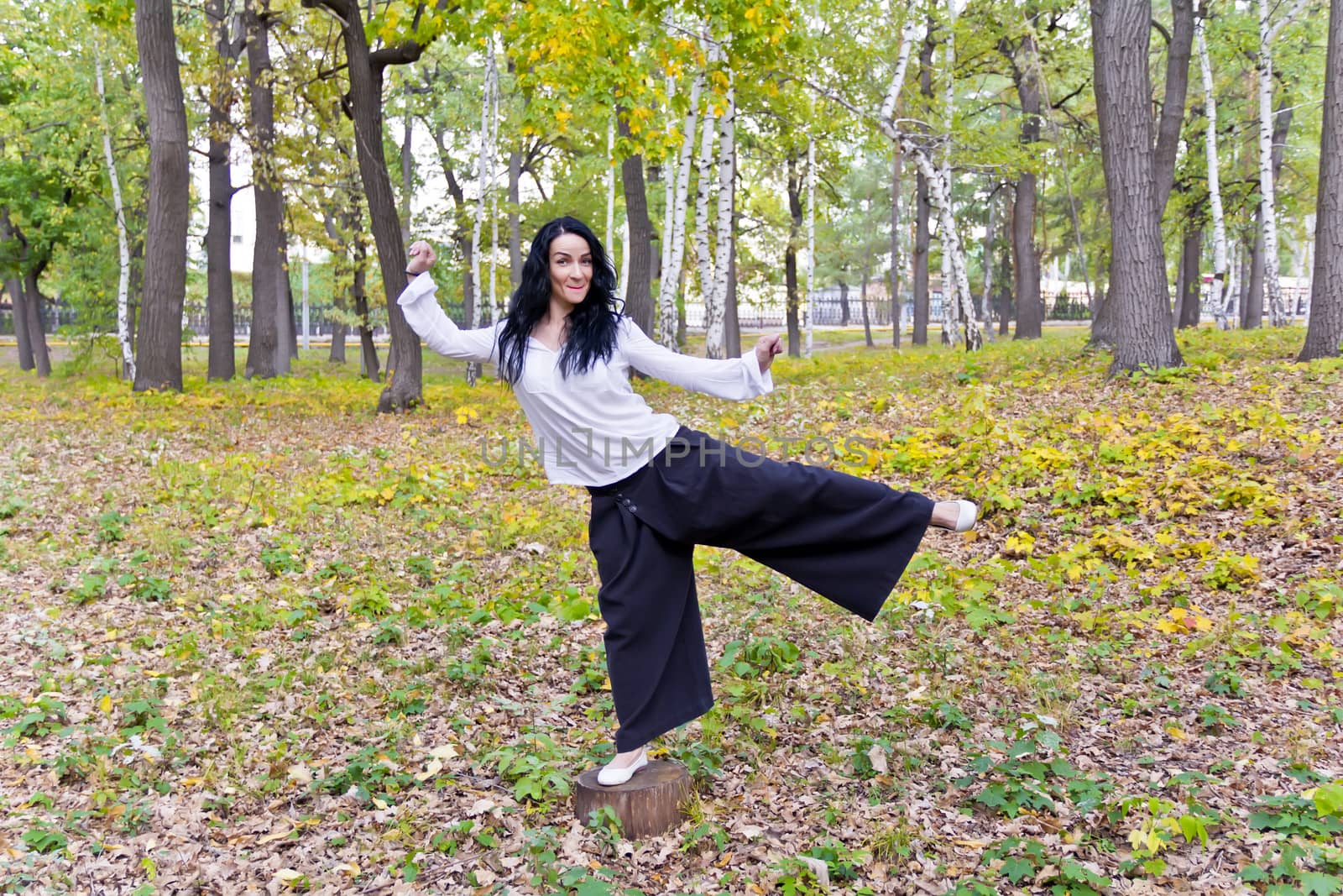 Beautiful brunette are standing on one leg in autumn park
