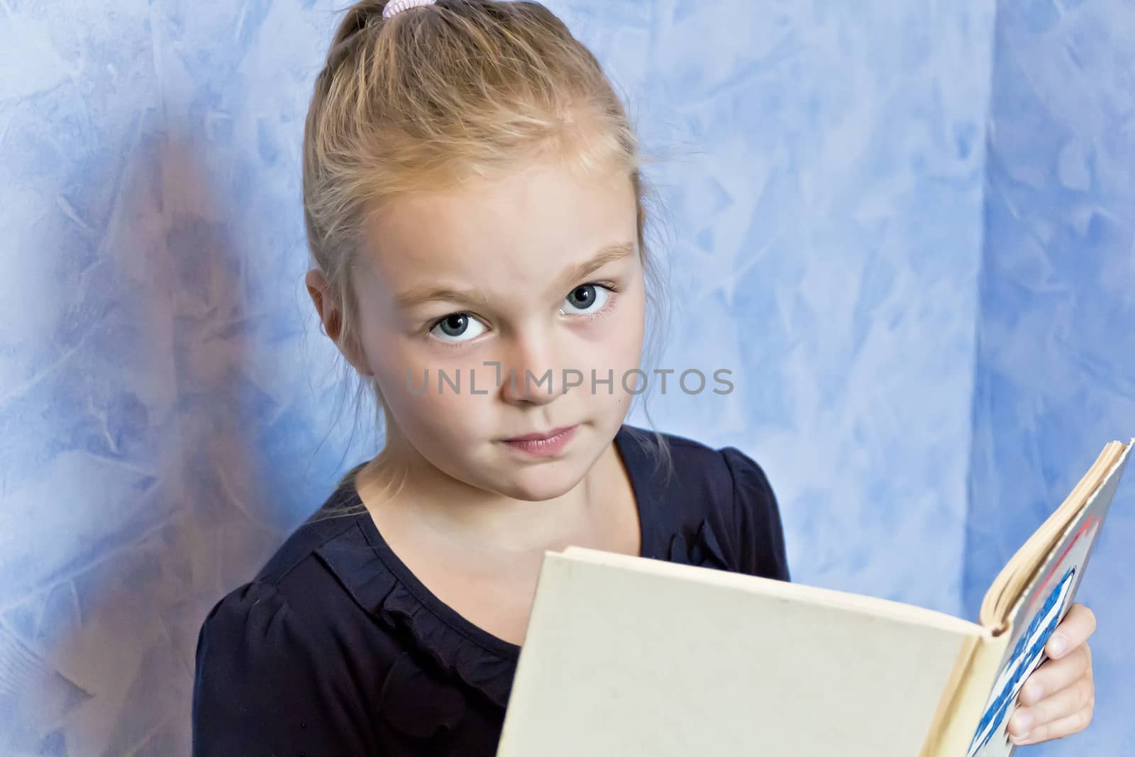 Cute smiling girl with blond hair are reading a book