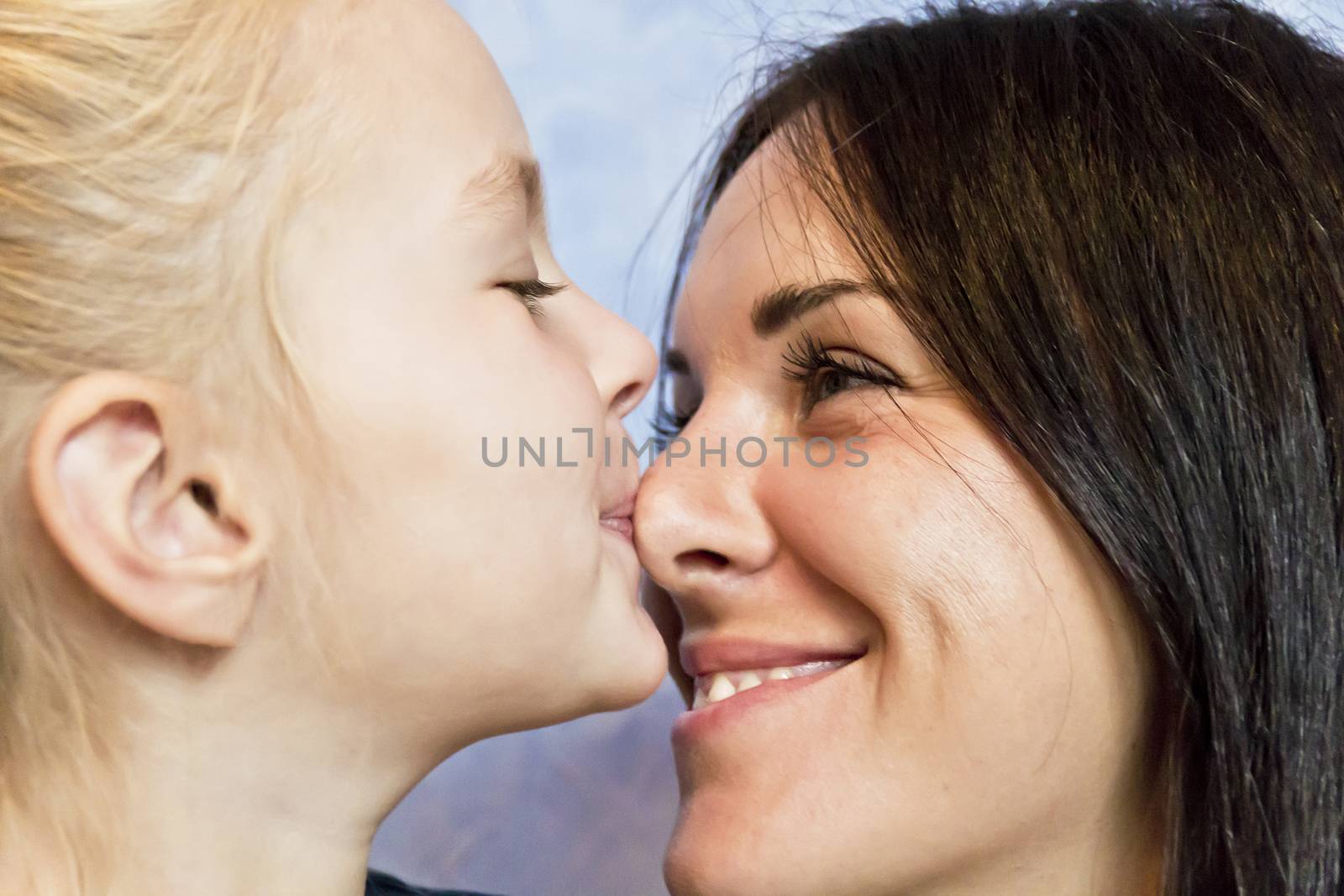 Cute smiling daughter kissing her mother to nose