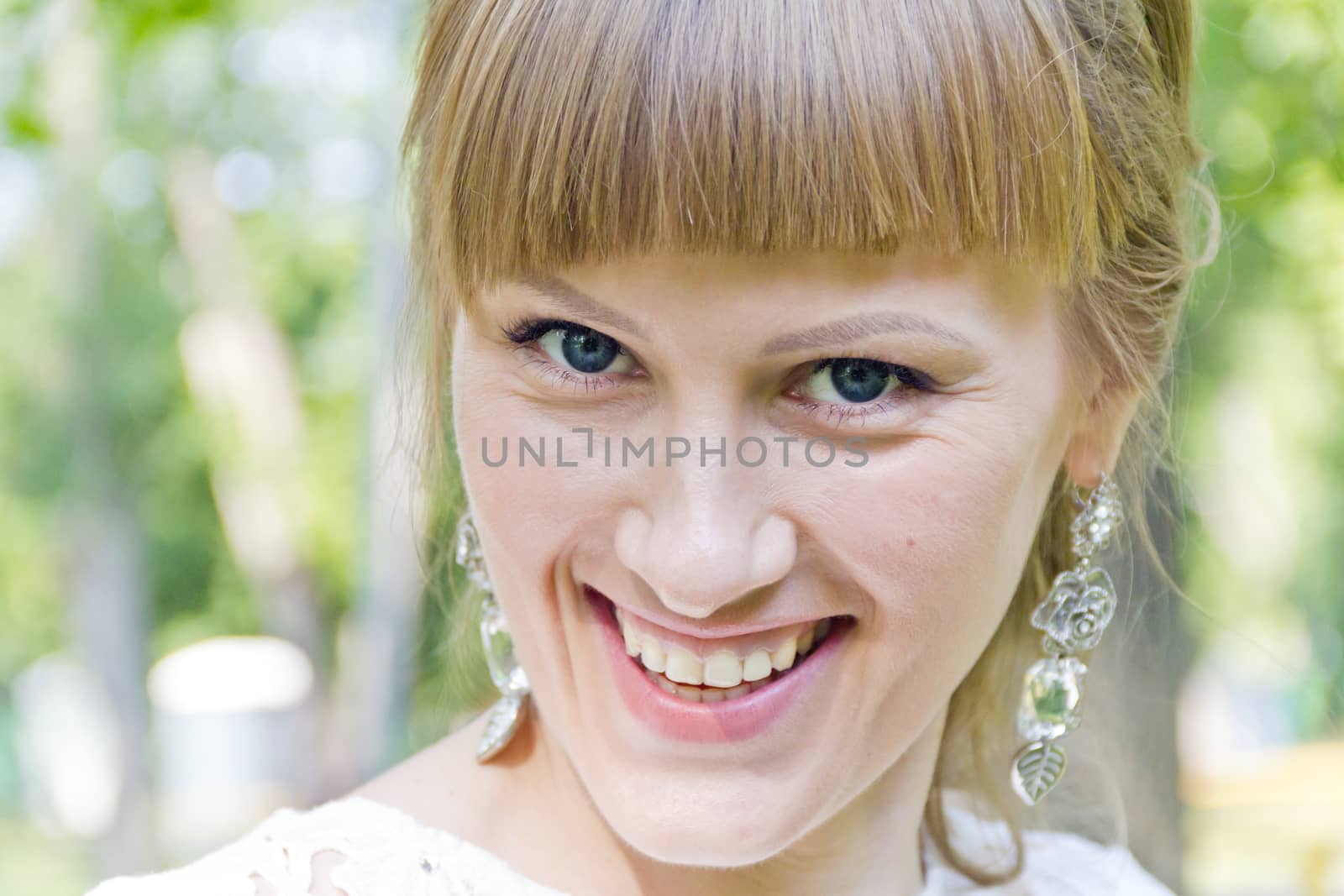 Horizontal portrait of smiling girl with blond hair on green background