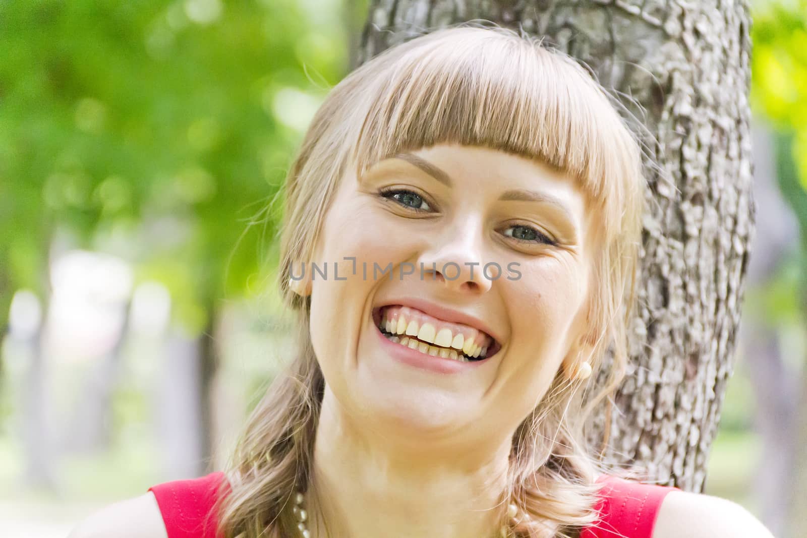 Portrait of smiling blond girl on green wood background