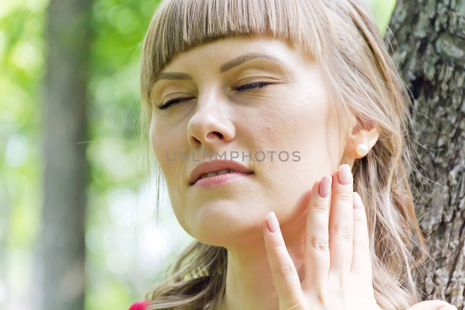 Portrait of blond girl with closed eyes on green wood background