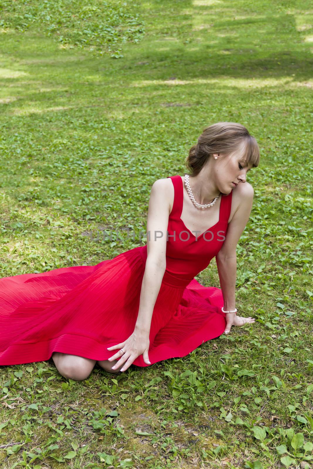 Beautiful lady in red are sittiing on green grass