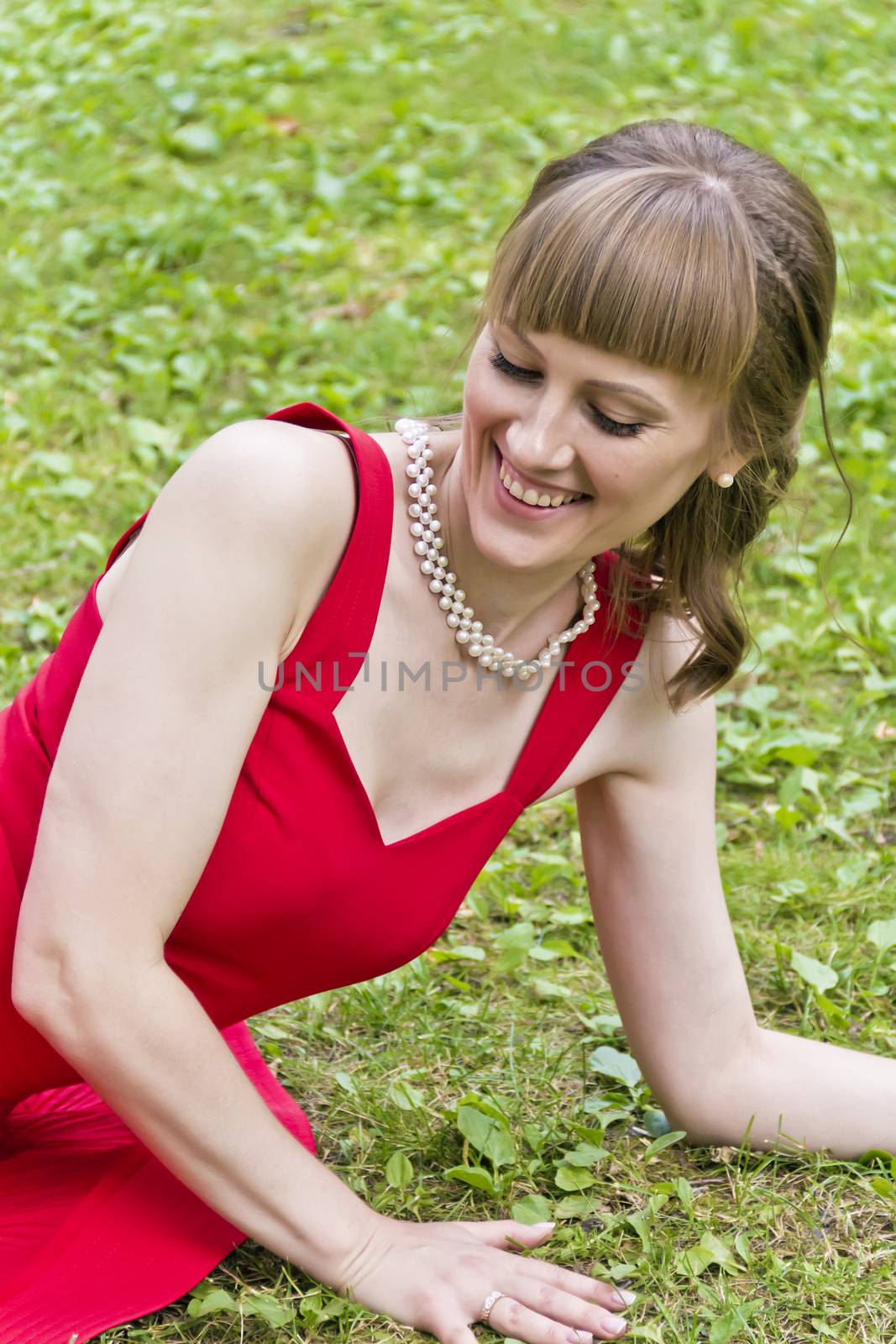 Beautiful lady in red are sittiing on green grass