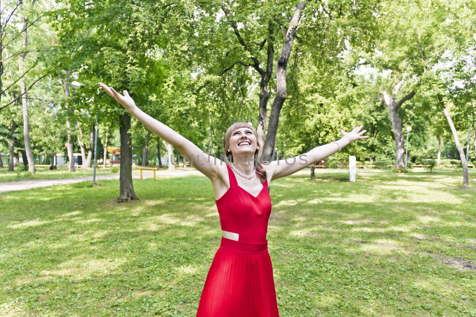 Beautiful lady in red are standing at summer day with upward hands