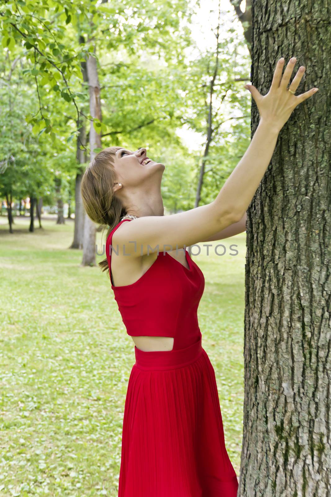 Beautiful lady in red are standing near tree summer day