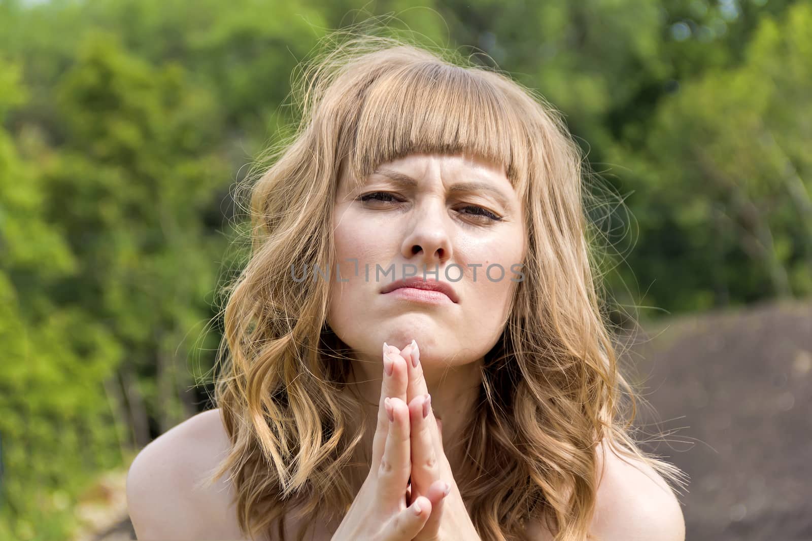 Young praying woman with blond hair in sunlight