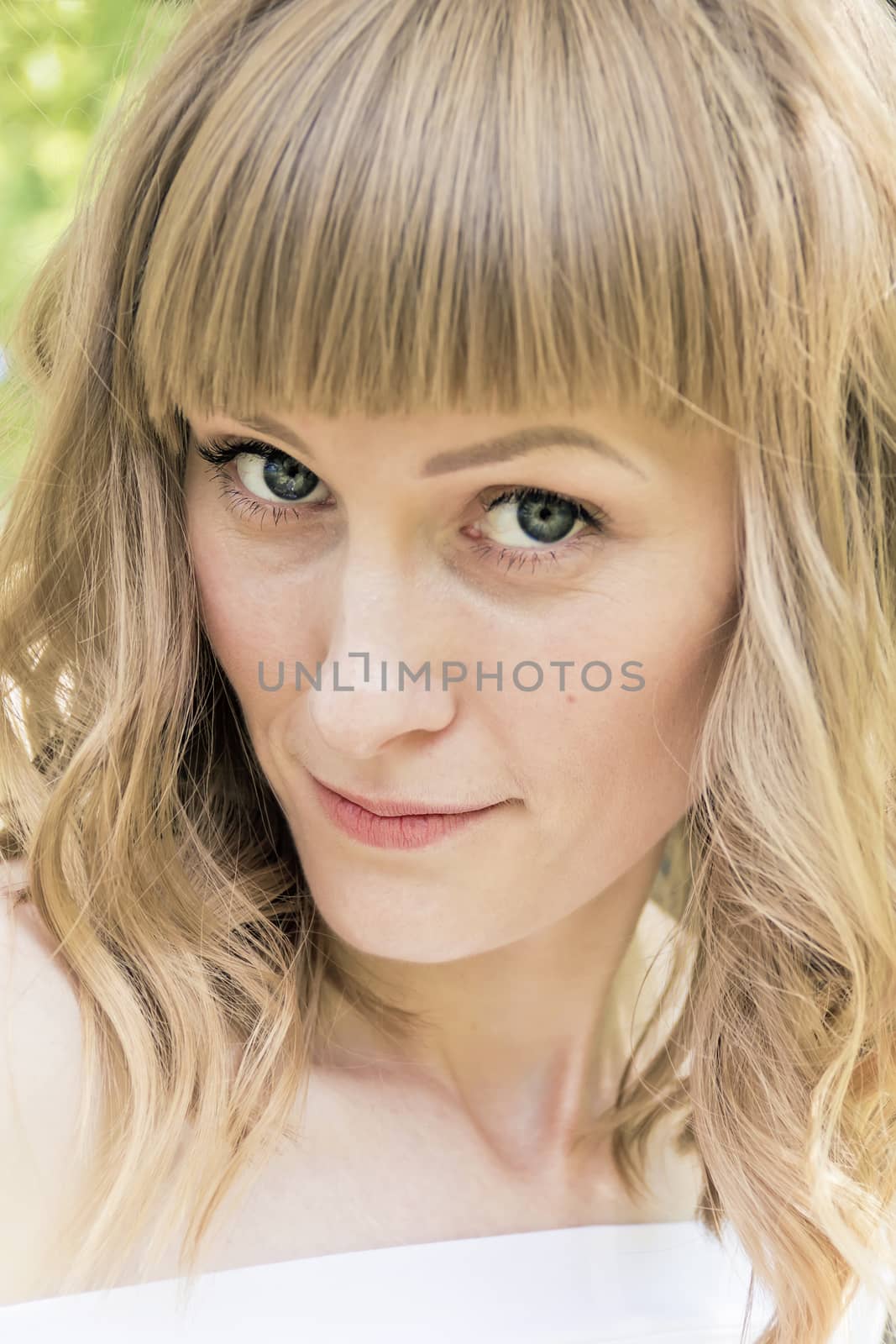 Vertical portrait of young woman with blond hair on sunlight background
