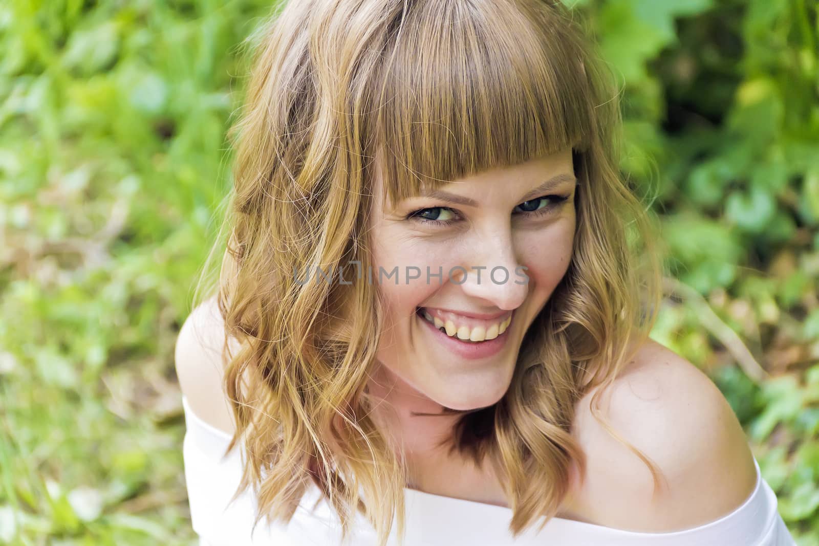 Portrait of laughing young woman with blond hair in sunlight
