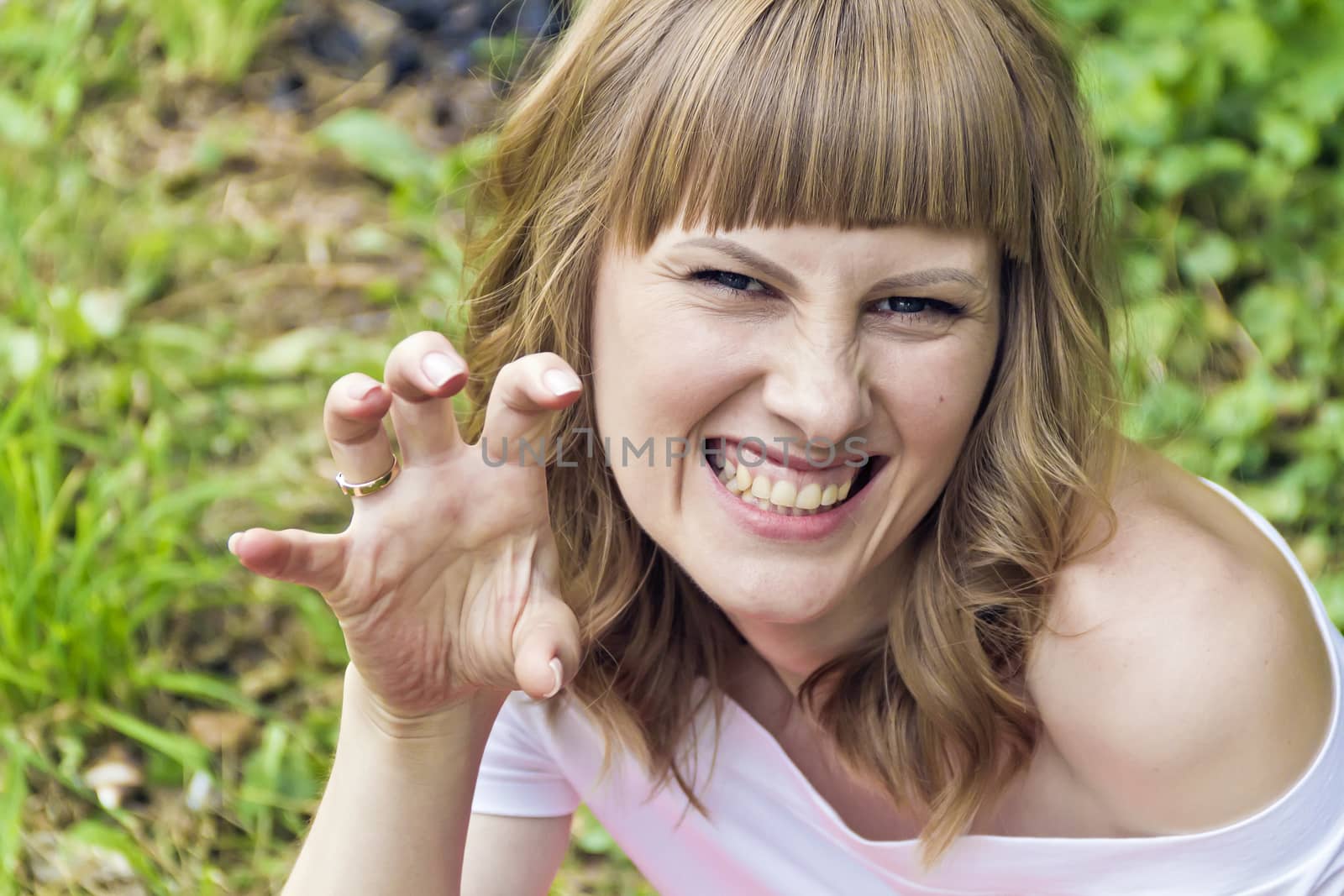 Horizontal portrait of evil woman with blond hair on summer background