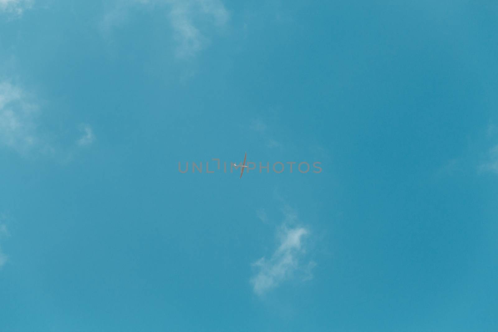 Glider gliding in blue sky from below.