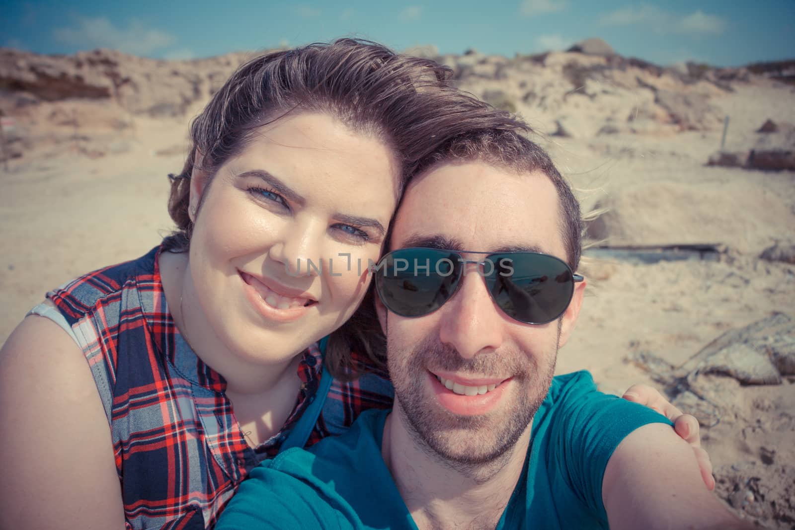 Young couple taking selfie with smartphone or camera at the beach.