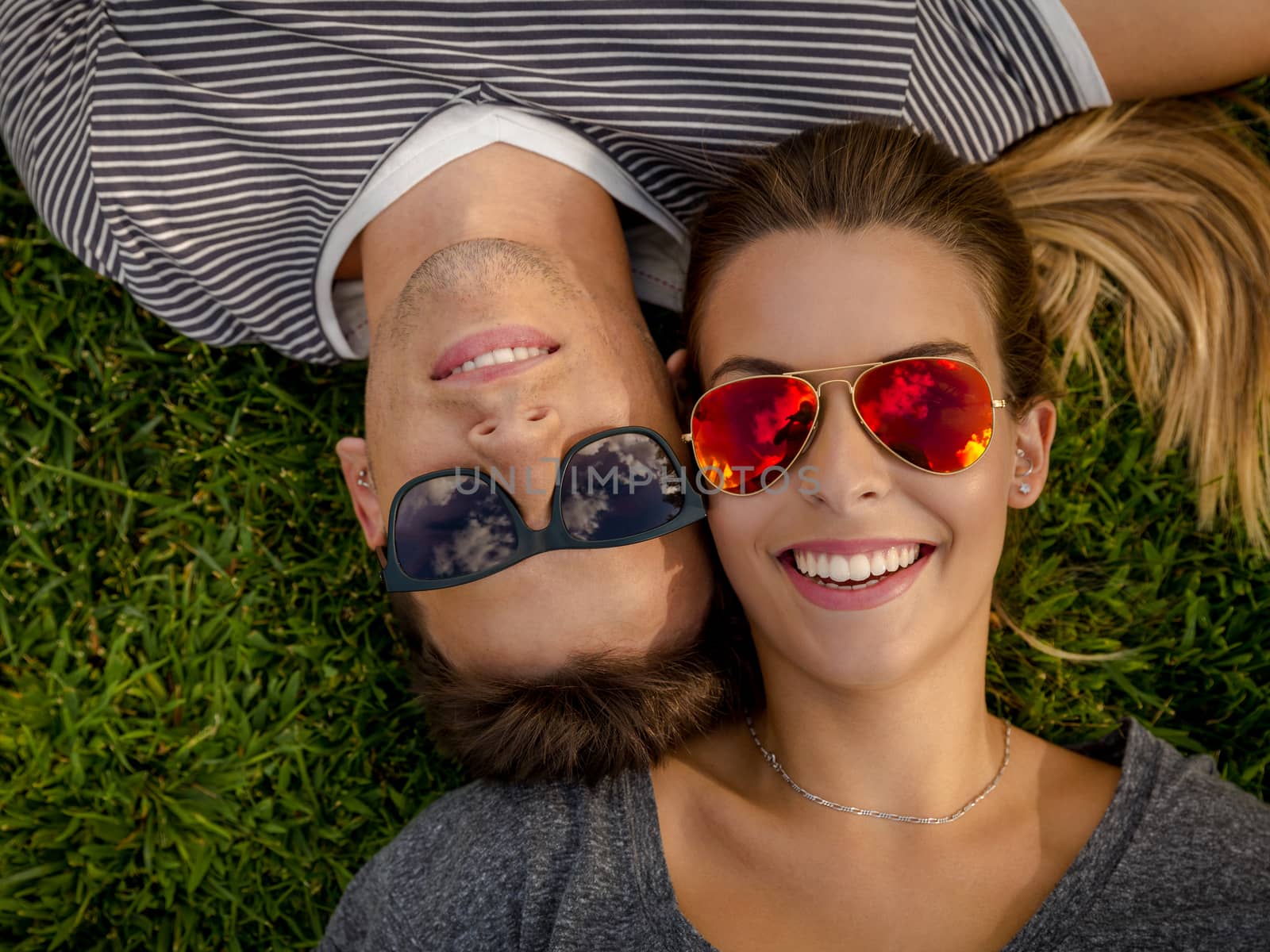 Portrait of a young beautiful couple lying on the grass