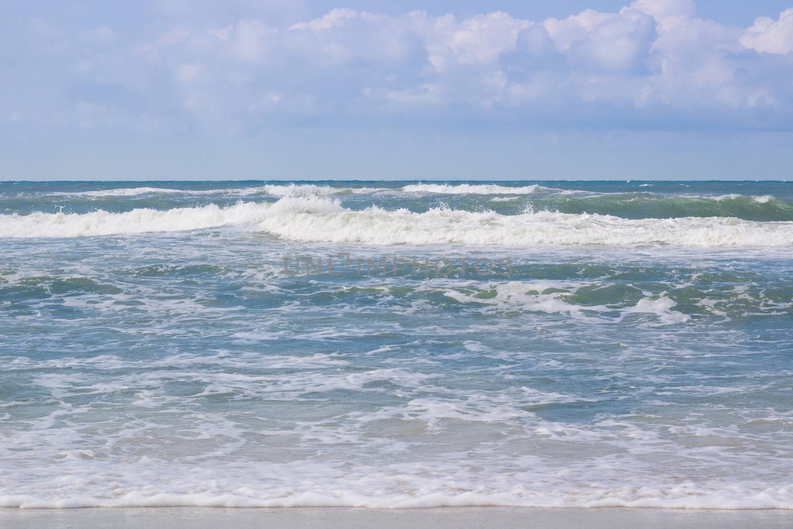 Sea coastal waves rolling on empty sandy beach, stormy cloudy sunrise skyview