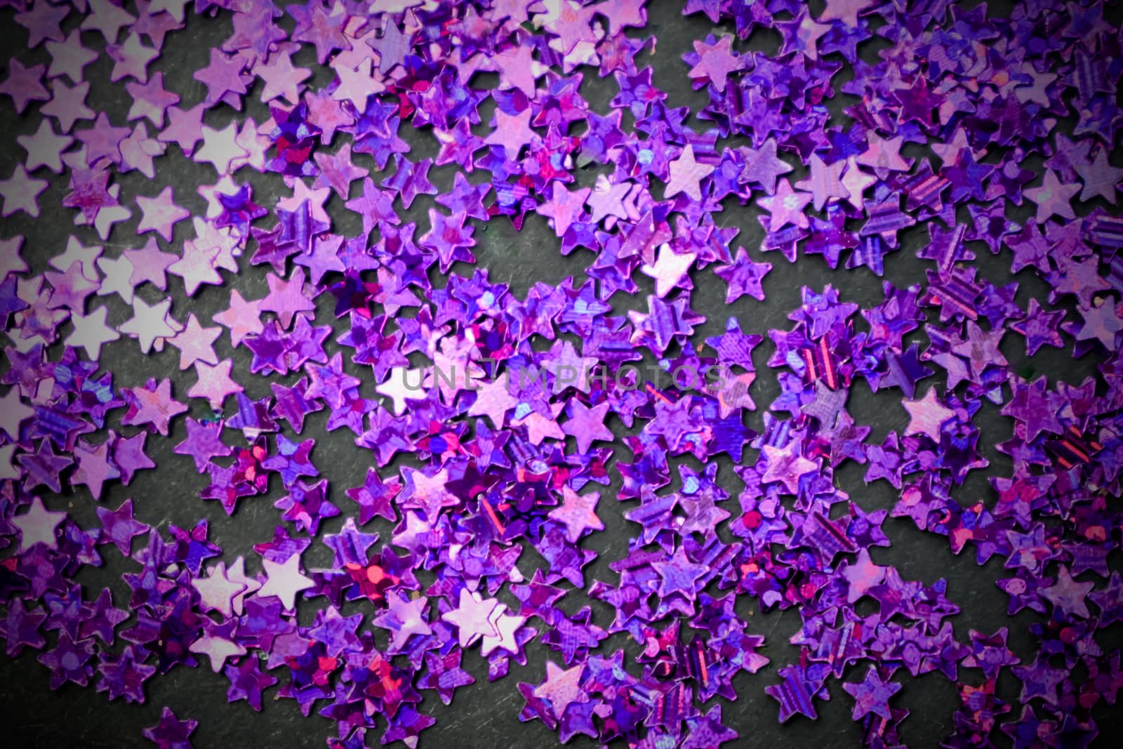 Purple glitter stars on a black background with copy space