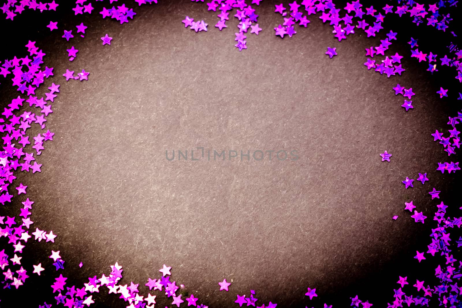 Purple glitter stars on a black background with copy space