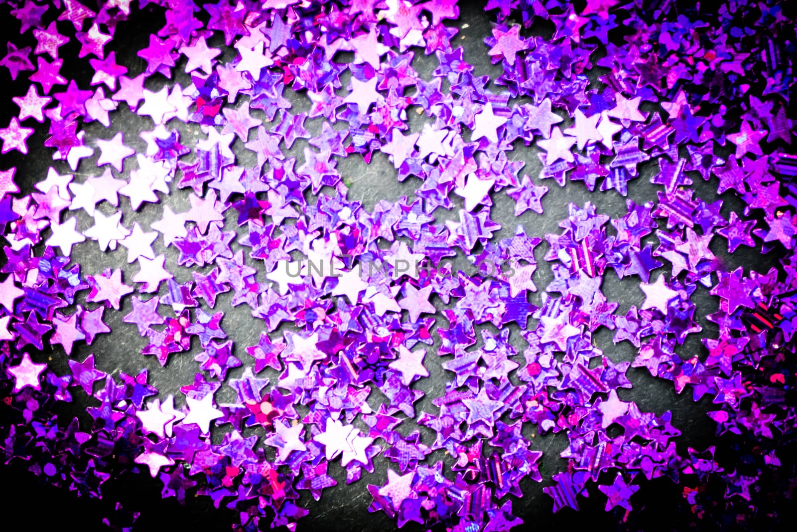 Purple glitter stars on a black background with copy space