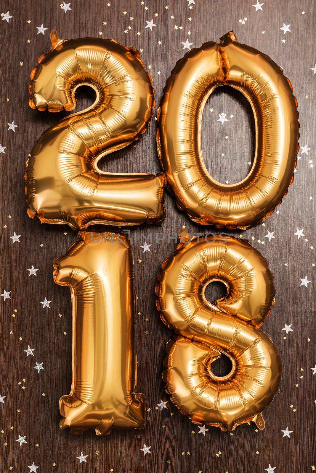 Bright gold balloons figures 2018, New Year Balloons with glitter stars on dark wood table background. Christmas and new year celebration