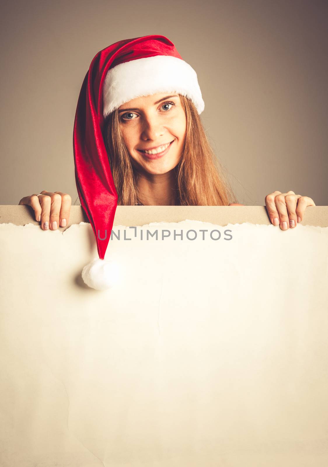 Santa girl holding blank vintage sign billboard. Christmas woman in Santa hat showing paper sign.